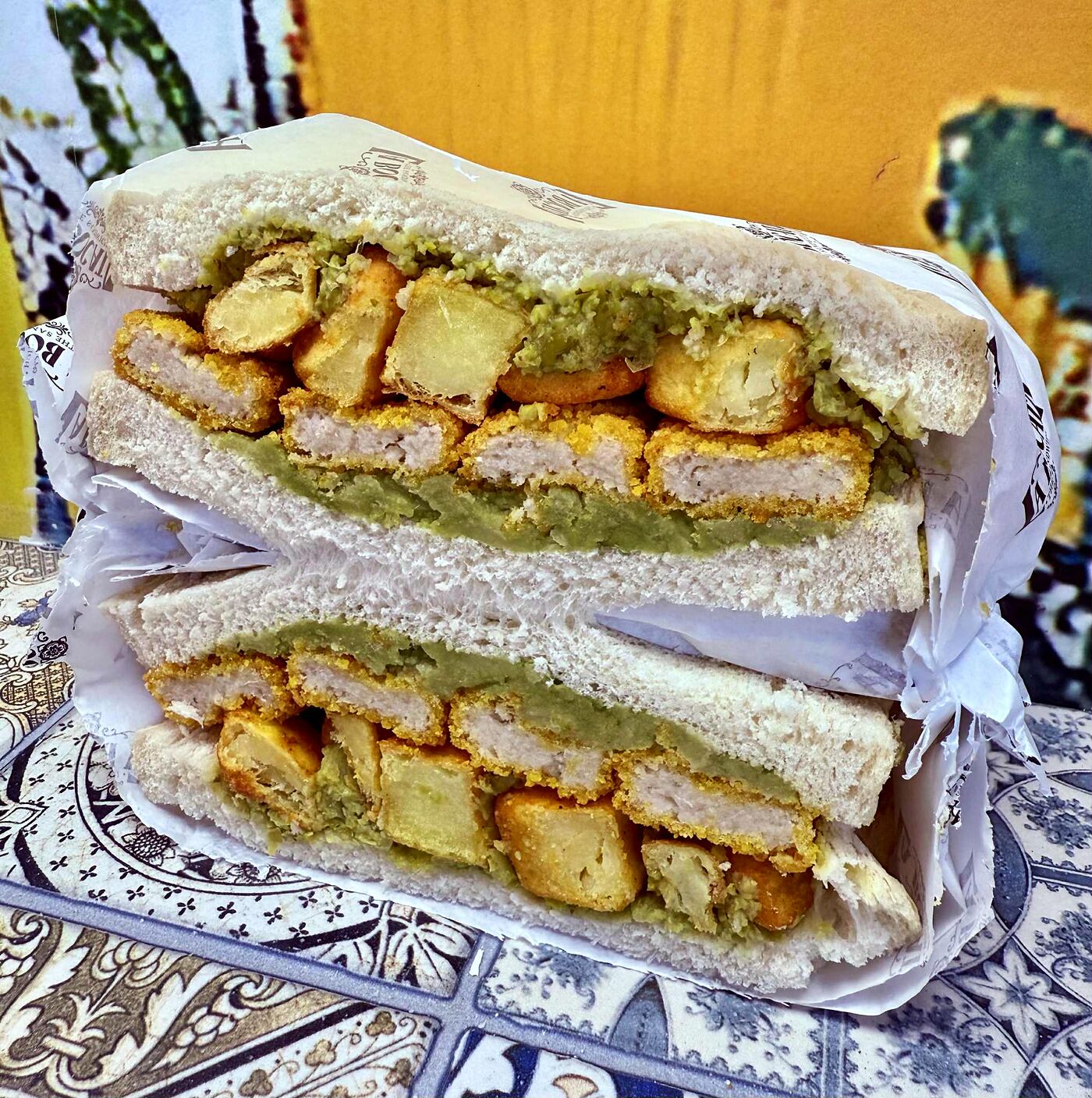 A breaded chicken bocata resting on a Spanish talavera-tile tablecloth