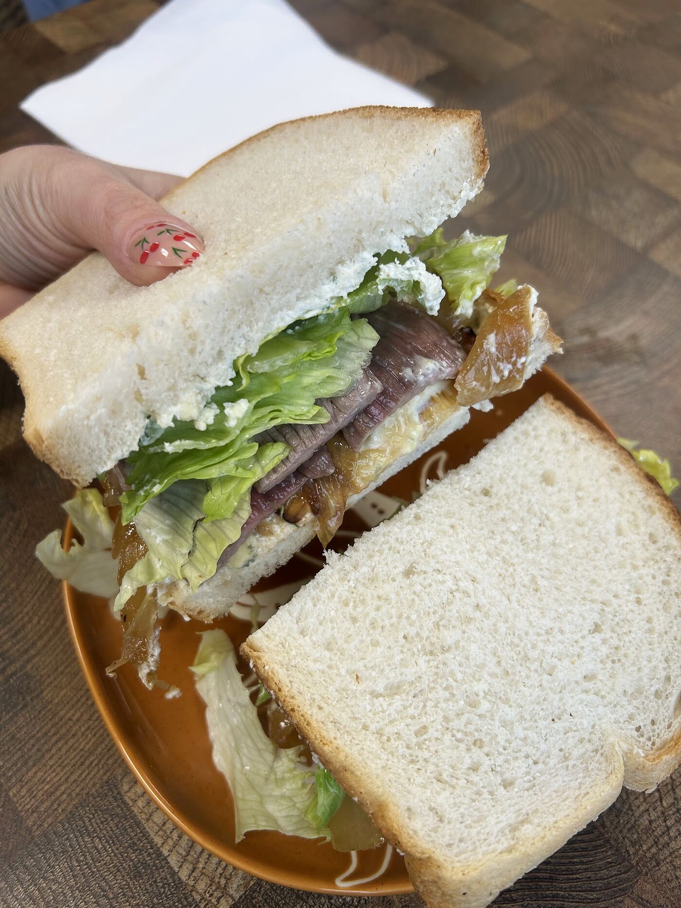 Half a bocata held above a terracotta plate, showing the fillings