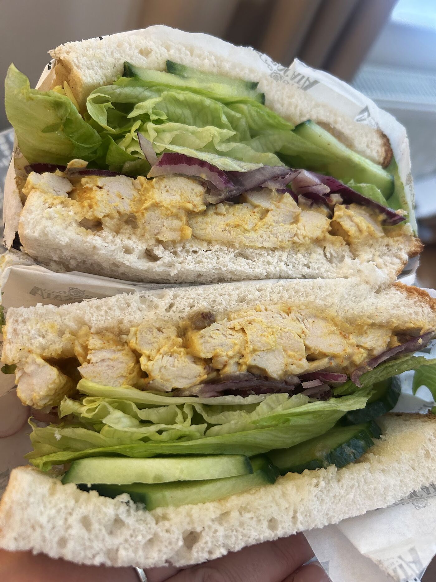 A halved bocata filled with breaded chicken, crisp lettuce and red onion