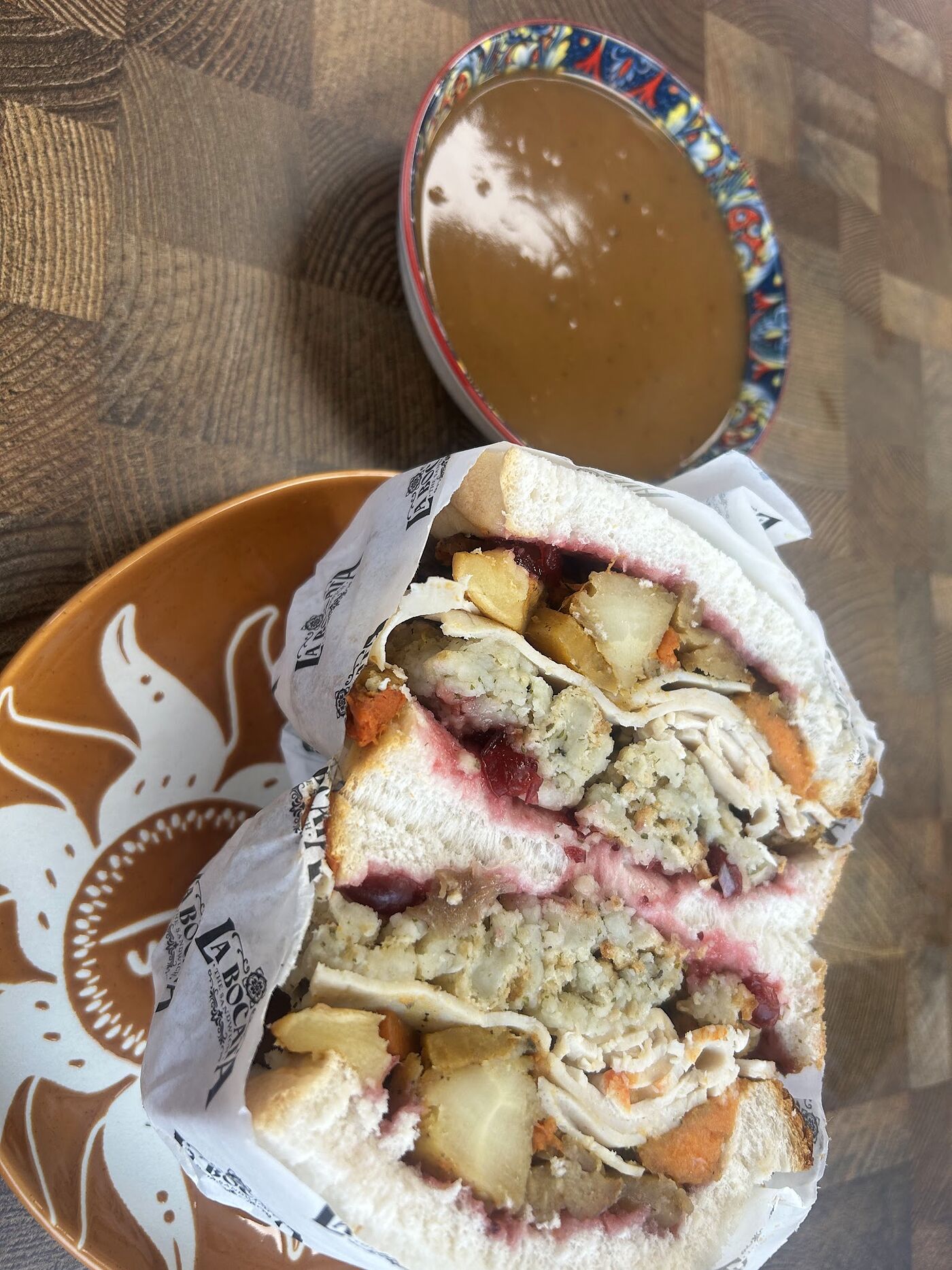 A roast-dinner style bocata on a terracotta plate beside a mug of thick Spanish hot chocolate