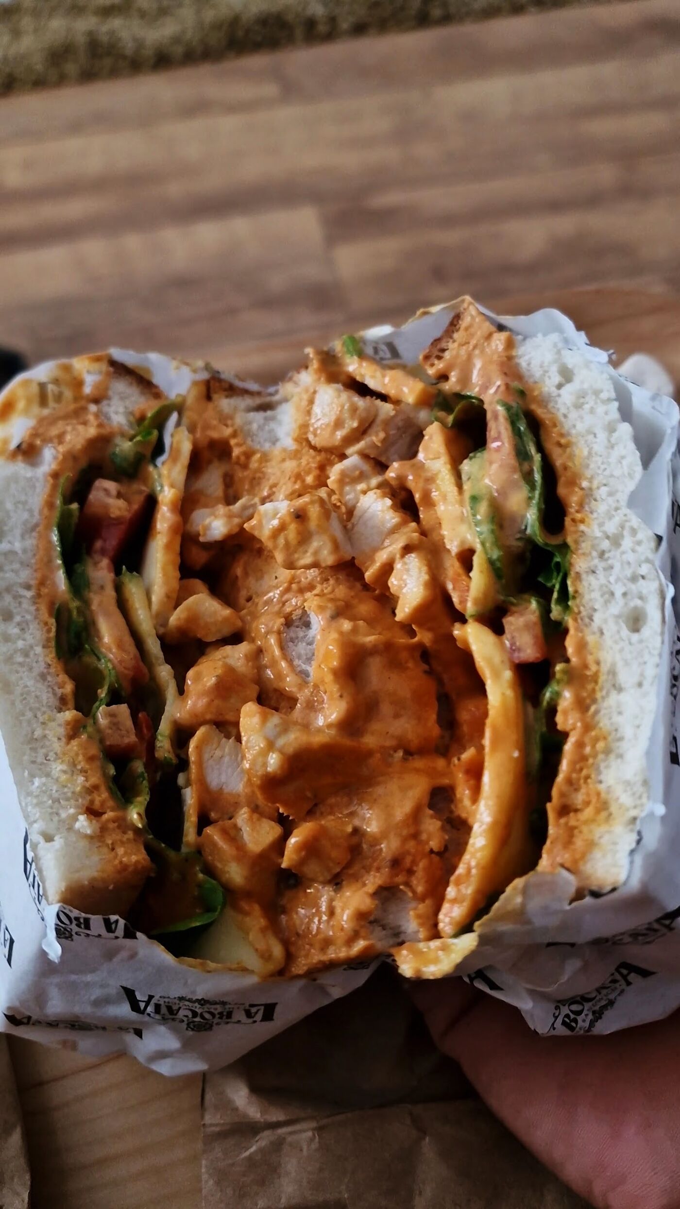 Close-up of a bocata packed with chicken in a rich sauce and fresh salad